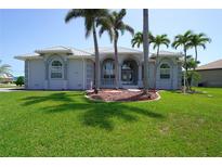 Charming single-story home with a landscaped front yard and beautiful curb appeal and mature palm trees at 649 Maltese Dr, Punta Gorda, FL 33950