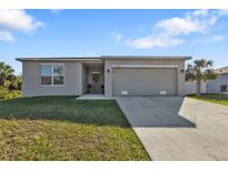 Charming single-story home featuring a well-maintained lawn, a gray color scheme, and a two-car garage at 18043 Avonsdale Cir, Port Charlotte, FL 33948
