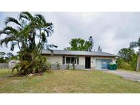 Front exterior of a single-story home with a driveway, some landscaping and palm trees at 11332 8Th Ave, Punta Gorda, FL 33955