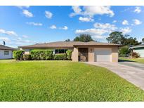 Tan house with a white garage door and well-maintained lawn at 1437 Rommel St, Port Charlotte, FL 33952