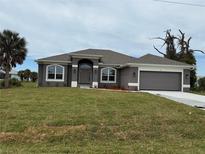 Charming single-Gathering home with gray exterior, arched windows, well-maintained lawn and two-car garage at 233 W Pine Valley Ln, Rotonda West, FL 33947