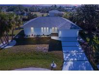 Aerial view of a single-story home with a gray roof and white exterior, showcasing a driveway and landscaping at 3004 Banyan Way, Punta Gorda, FL 33950