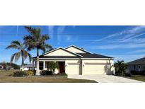 Charming single-story home with a two-car garage, red front door, and lush landscaping at 25228 Nocturne Ln, Punta Gorda, FL 33983