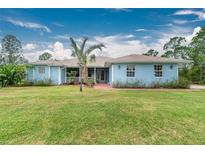 Light blue house with palm trees and a brick walkway at 27545 Monte Cristo Blvd, Punta Gorda, FL 33955