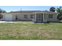 Charming single story home with a simple front yard and an attached garage on a sunny day at 21471 Dranson Ave, Port Charlotte, FL 33952