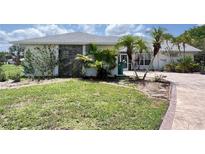 Charming home with a stone accent wall, lush landscaping, and a patterned driveway leading to the entrance at 1438 Razorbill Ln, Punta Gorda, FL 33983