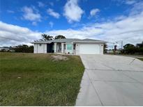 Charming single-story home with a paved driveway and lush green lawn at 200 Dolphin Pkwy, Punta Gorda, FL 33950