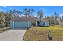 Charming blue home with attached two-car garage and landscaped front yard at 18359 Gypsy Ave, Port Charlotte, FL 33954