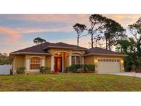 Charming single-story home with a two-car garage and landscaped front yard at sunset at 3100 Sheboygan Ave, North Port, FL 34286