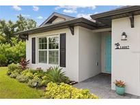 White house with teal door, landscaping, and paved walkway at 14087 Fillmore Ave, Port Charlotte, FL 33981