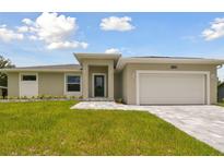 Newly constructed home with a two-car garage and landscaped lawn at 18854 Ackerman Ave, Port Charlotte, FL 33948