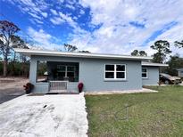 Newly renovated single story home featuring a gray exterior, covered porch, and landscaped yard at 27240 Tribune Blvd, Punta Gorda, FL 33955
