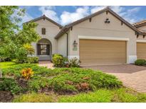 Beige two-story house with a two-car garage and landscaped front yard at 11137 Mcdermott Ct, Englewood, FL 34223
