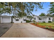 White brick house with black and white awnings, a large driveway, and a well-manicured lawn at 330 45Th S St, St Petersburg, FL 33711