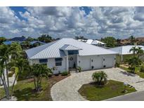 Beautiful single-story home with a metal roof, manicured lawn, and three-car garage on a sunny day at 2750 W Marion Ave, Punta Gorda, FL 33950