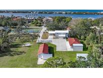 Aerial view of home, detached garages, and tennis court with water views at 1931 Bayshore Dr, Englewood, FL 34223