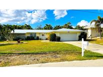 Ranch-style home with a metal roof, landscaped lawn, and attached garage at 3029 Buttonwood Pl, Punta Gorda, FL 33950