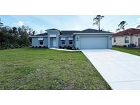 Charming single-story home featuring a well-manicured lawn, gray exterior, and a two-car garage at 5587 E Price Blvd, North Port, FL 34288