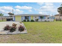 Charming ranch home with a yellow door and nicely landscaped lawn at 817 E 6Th St, Englewood, FL 34223