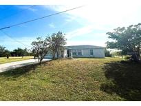 Inviting single-story home with a well-manicured lawn, mature trees, and light-colored exterior at 12143 Du Barry Ave, Port Charlotte, FL 33981