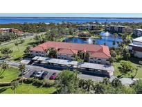Beautiful aerial view of condo complex with red tile roof, lake, fountains, and waterfront views at 23465 Harborview Rd # 1006, Punta Gorda, FL 33980