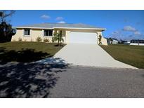 Charming one-story home with a well-manicured lawn, a freshly painted driveway, and a two-car garage at 102 Annapolis Ln, Rotonda West, FL 33947