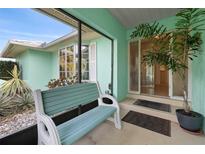Inviting enclosed porch with a comfortable bench, stylish decor, and a welcoming entrance to the home at 1845 Edison Dr, Englewood, FL 34224