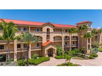 Beautiful condo building with red roof, balconies and lush tropical landscaping at 89 Vivante Blvd # 205, Punta Gorda, FL 33950