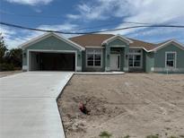 Charming single-story home with light green exterior, brown roof, and an attached two-car garage at 8599 Waldrep St, Port Charlotte, FL 33981