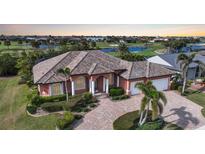 Stunning custom home features a paver driveway, barrel tile roof, and lush landscaping and pond views at 3977 La Costa Island Ct, Punta Gorda, FL 33950