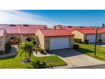 Charming villa featuring a vibrant red metal roof, an attached garage, and a well-manicured lawn at 1780 Deborah Dr # 15, Punta Gorda, FL 33950