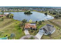 Aerial view of a waterfront property with a screened pool, lush landscaping, and proximity to a tranquil lake at 1115 Venture Ct, Punta Gorda, FL 33983