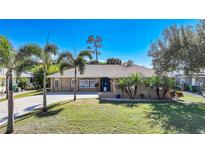 Charming single-story home featuring well-manicured lawn, mature palms and stone accents at 18395 Edgewater Dr, Port Charlotte, FL 33948