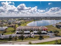 An aerial view of condos and covered parking near a lake with blue sky and scattered clouds at 26397 Nadir Rd # 208, Punta Gorda, FL 33983