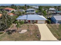 Charming single-story home with a metal roof, attached garage, and well-maintained front yard on a canal at 520 Boardman Dr, Punta Gorda, FL 33950