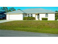 Well-maintained single-story home with a two-car garage, manicured lawn, and arched windows at 1426 Natrona Dr, North Port, FL 34286