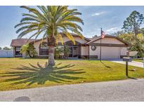 Charming one-story home featuring a palm tree in the front yard, a two-car garage and an American flag at 23239 Stelling Ave, Punta Gorda, FL 33980