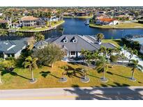 Expansive waterfront home with lush landscaping and a private boat dock, showcasing luxury coastal living at 3415 Tripoli Blvd, Punta Gorda, FL 33950