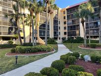 Beautiful multi-story condo building with tropical landscaping and palm trees along the walkway at 3006 Caring Way # 409, Port Charlotte, FL 33952