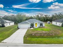 Charming single-story home with a well-manicured lawn, light gray paint, gray roof, and a bright yellow front door at 3264 Garbett Ter, North Port, FL 34288