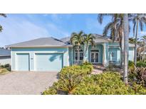 Charming light blue home with a brick driveway, lush landscaping and a two-car garage at 960 Messina Dr, Punta Gorda, FL 33950