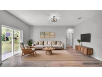 Bright, neutral living room featuring a comfortable sofa, stylish decor, and sliding glass doors at 1117 Vernon Ave, Port Charlotte, FL 33948