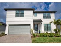 Charming two-story home featuring a gray two-car garage, landscaped yard, and a covered front entryway at 2208 Darley Oak Way, North Port, FL 34289