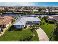Stunning waterfront home with a metal roof, lush landscaping, and a private dock on a sunny day at 936 Lassino Ct, Punta Gorda, FL 33950