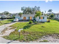 Charming single-story home with a well-maintained lawn, lush palm trees, and canal access at 3000 Wisteria Pl, Punta Gorda, FL 33950