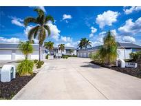 Wide driveway leading to condo garages with lush landscaping and blue sky at 1340 San Cristobal Ave # 305, Punta Gorda, FL 33983