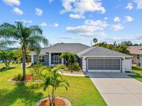 Well-maintained single-story home with a gray exterior, screened garage, lush landscaping and inviting curb appeal at 27191 Tierra Del Fuego Cir, Punta Gorda, FL 33983