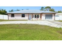 Charming single-story home with a metal roof, a well-manicured lawn, and an attached two-car garage at 4520 Knollwood Dr, Punta Gorda, FL 33982