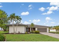 Beautiful single-story home featuring a well-manicured lawn, mature landscaping, and an attached two-car garage at 1301 Appian Dr, Punta Gorda, FL 33950