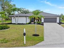 Charming one-story home with a well-manicured lawn and mature palm trees. Attached two-car garage and fresh landscaping at 1301 Appian Dr, Punta Gorda, FL 33950